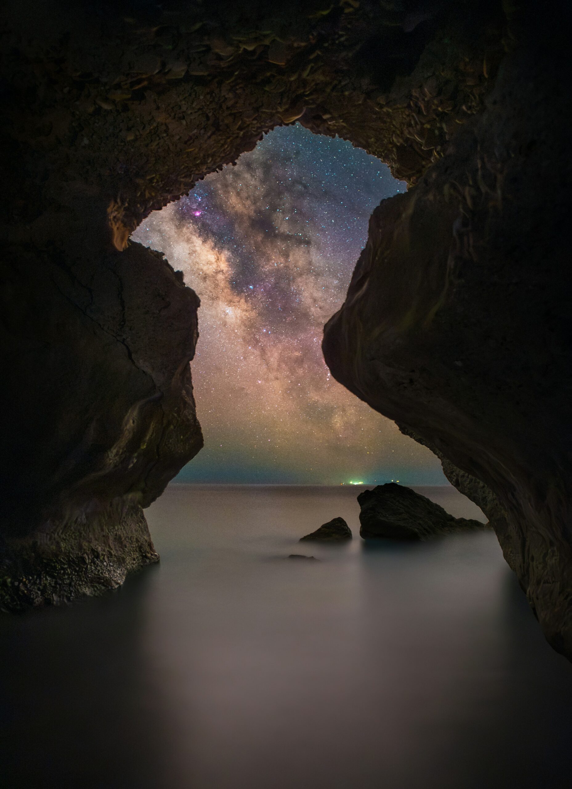 Photo: Mysterious ocean cave, calm water, opens to night sky, Milky Way.